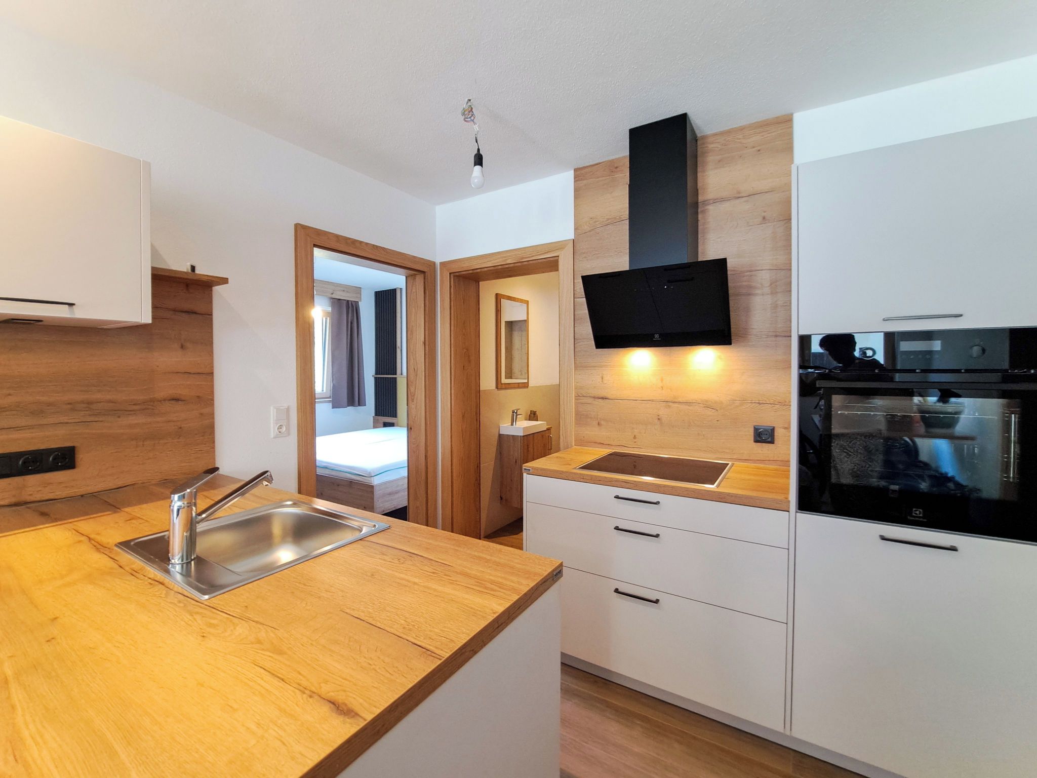 Een moderne keuken met houten aanrecht, een ingebouwde oven en een flatscreen televisie aan de muur.