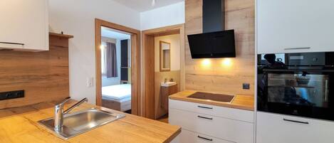 A modern kitchen with wooden countertops, a built-in oven, and a flat-screen TV mounted on the wall.