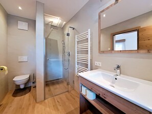 A modern bathroom with a glass shower enclosure, a white sink, and a wooden vanity. - Apartment Tyrol by Interhome (Auffach)