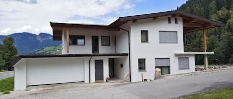 Una casa moderna de dos pisos con garaje, un porche cubierto y vistas a las montañas.
