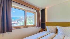 Une chambre d’hôtel avec un lit, une fenêtre avec des rideaux et une vue sur une zone boisée.
