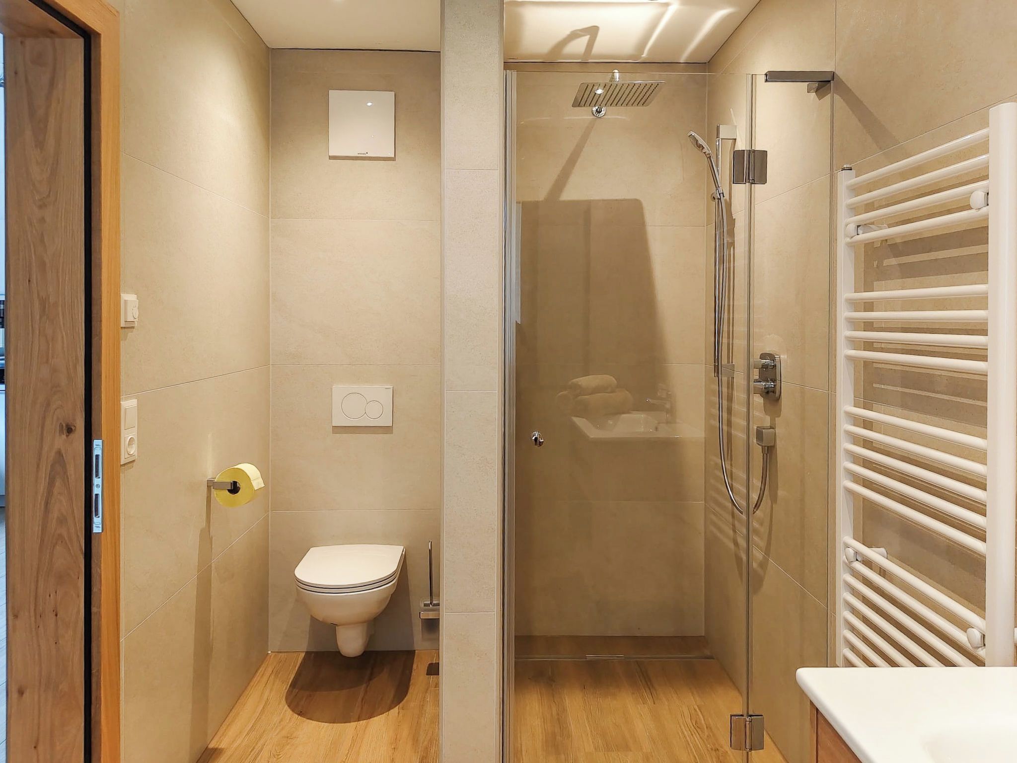 Une salle de bain moderne équipée de toilettes, d’une douche et d’un porte-serviettes.
