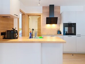 A modern kitchen with a wooden countertop, a built-in oven, and a wall-mounted TV. - Bavaria by Interhome (Auffach)