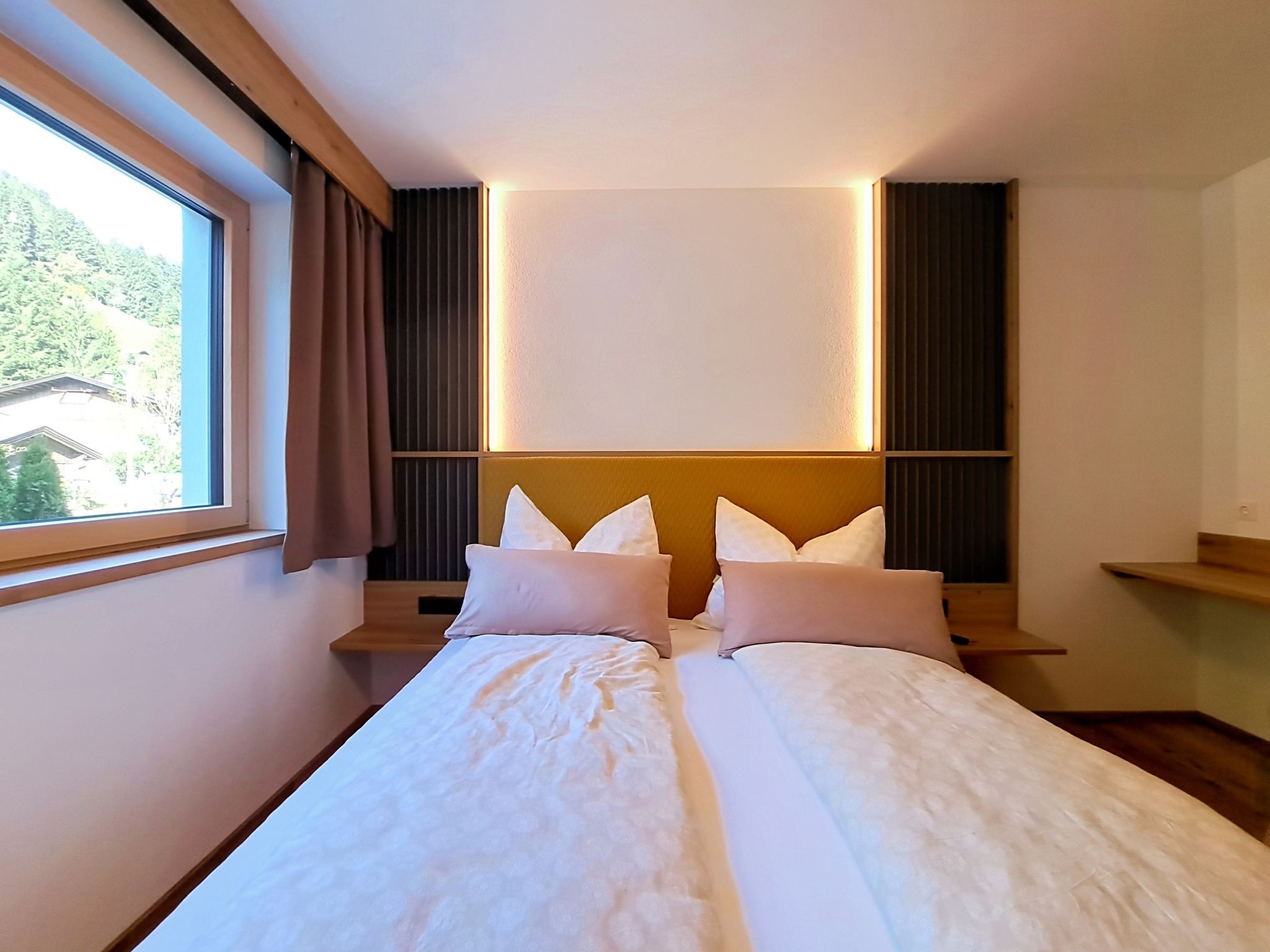 Un lit double avec une tête de lit, des tables de chevet et une fenêtre avec des rideaux.