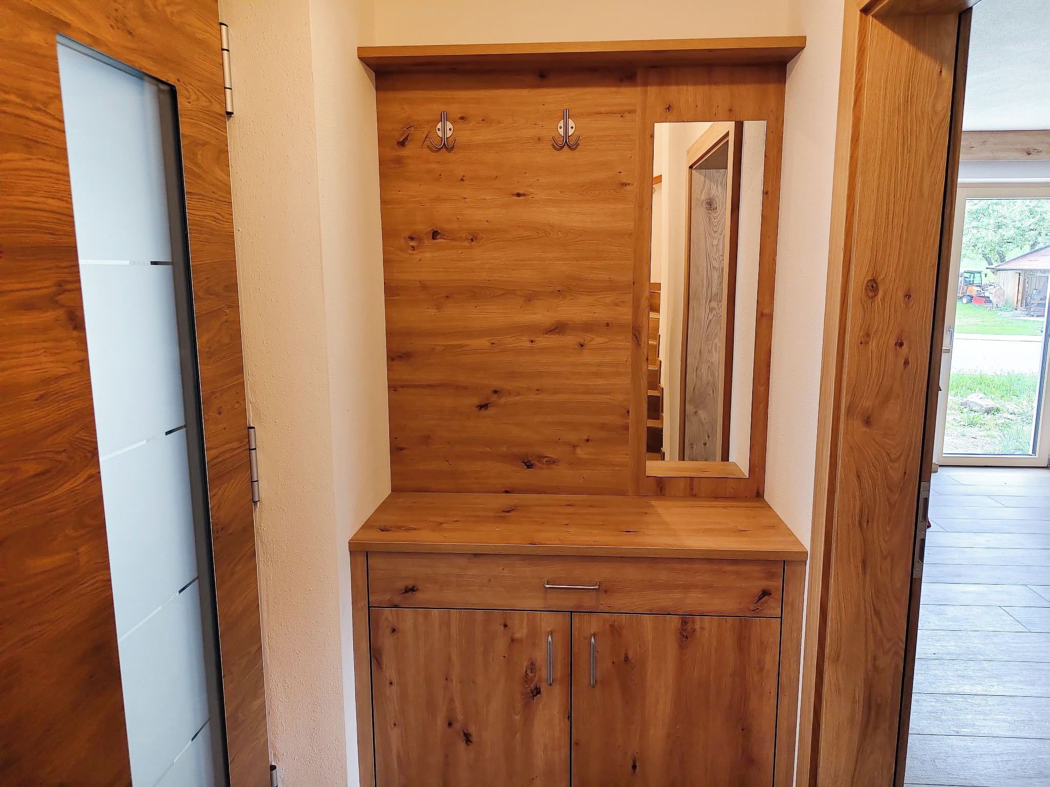 A wooden cabinet with a mirror, a door, and a small drawer.