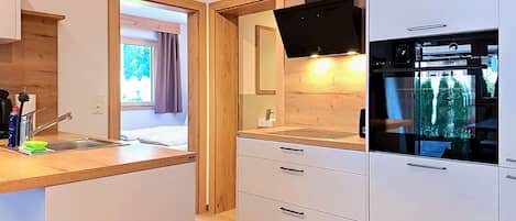 Een moderne keuken met een inbouwoven, een spoelbak en een raam met gordijnen.