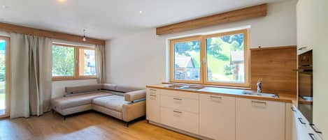 A modern kitchen with a built-in island, wooden flooring, and large windows.