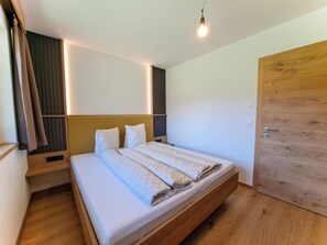 Ein Einzelbett mit Kopfteil, Holzboden, eine Tür und eine Leuchte.