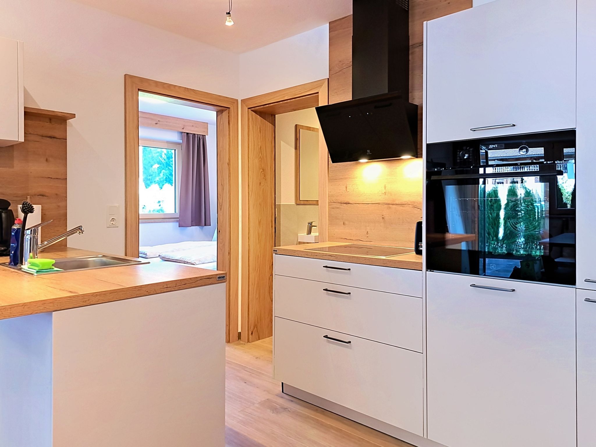 Een moderne keuken met een inbouwoven, een spoelbak en een raam met gordijnen.