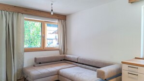 Quarto com sofá de canto, um armário de madeira e janela com cortinas.