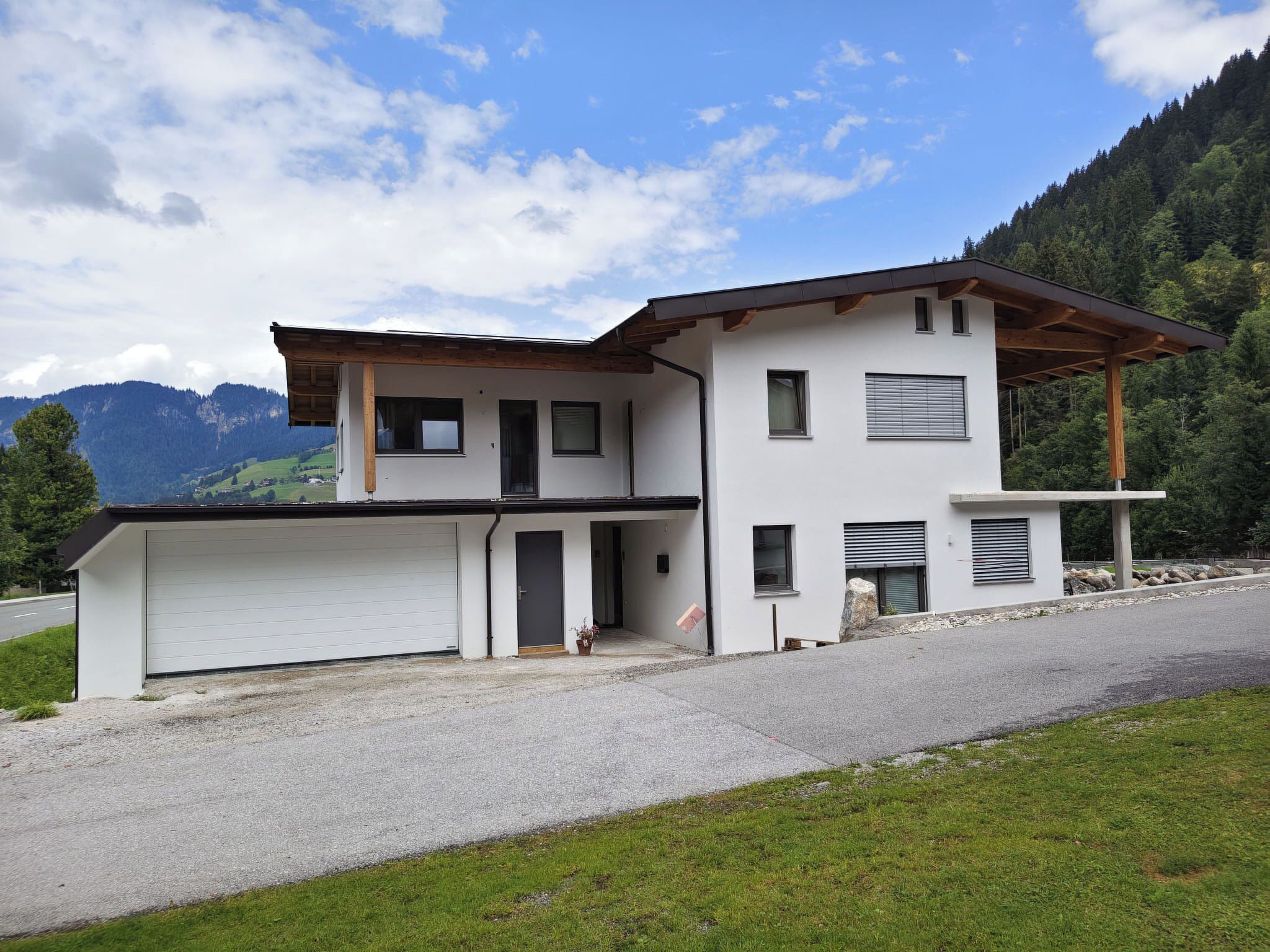 Une maison moderne à deux étages, dotée d’un garage, d’un porche abrité et offrant une vue sur les montagnes.