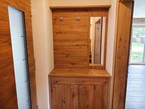 Ein Holzkabinent mit Spiegel, Tür und kleiner Schublade.
