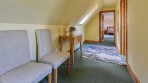 A hallway with a bench, a small table with a vase, and a view into another room. - Bunloit Loft by Interhome (Drumnadrochit)
