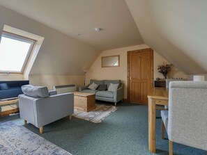 A cozy loft bedroom with a sloped ceiling, a sofa, a small table, and a window. - Bunloit Loft by Interhome (Drumnadrochit)