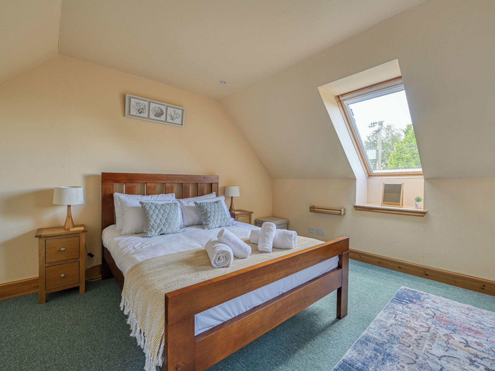 Ein Schlafzimmer mit einem hölzernen Bett, einem Nachttisch, einer Lampe, einem Fenster mit Blick und einem kleinen Regal mit einer Pflanze.