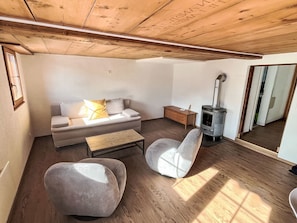 A cozy living room with a sofa, a chair, a small table, and a wood-burning stove.