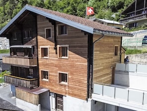 A multi-story wooden building with balconies and a Swiss flag.