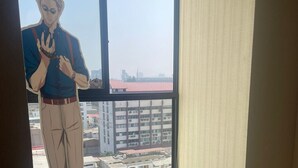 A room with a large window, a view of buildings, and a figure standing by the window. - Anime apartment in Lima (Lima)