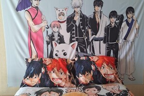 Una cama con un edredón que presenta personajes de anime.