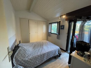 A bedroom with a bed, a wardrobe, a window with curtains, and a small table with items. - House in Hossegor, 200 meters from the main beach (Soorts-Hossegor)
