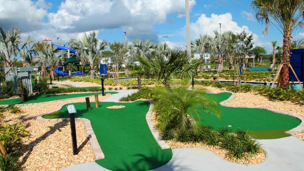 Un campo de golf con un fairway verde, búnkeres de arena y un obstáculo de agua.