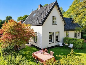 A white house with a black roof, surrounded by a well-maintained garden and a dining area with a table and chairs. - Lovely Holiday Home Centrally Located in Bergen in Delightful Surroundings (Bergen)