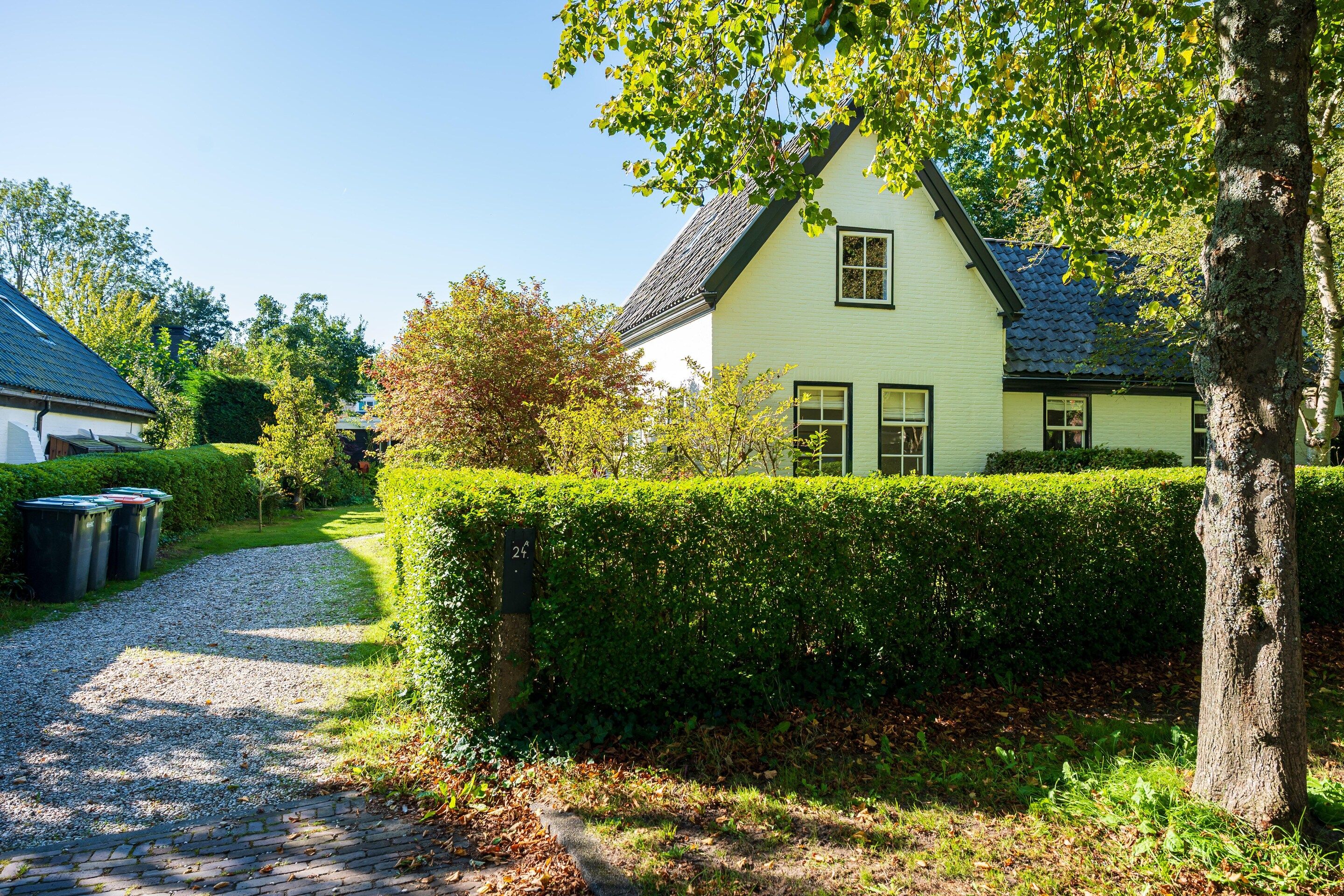 Ein charmantes Haus mit Kiesweg, umgeben von üppigem Grün und einer gepflegten Hecke.