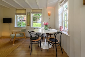 A dining area with a round table, four chairs, a vase with flowers, and a television mounted on the wall. - Lovely Holiday Home Centrally Located in Bergen in Delightful Surroundings (Bergen)