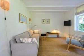 Un salon moderne avec un canapé, une petite table, une lampe et un téléviseur.