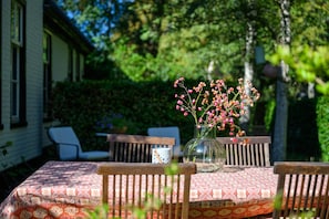 A table with a patterned tablecloth, a vase with pink flowers, and a chair. - Lovely Holiday Home Centrally Located in Bergen in Delightful Surroundings (Bergen)