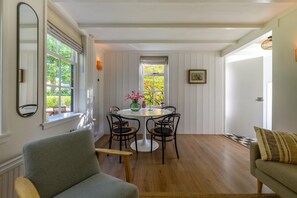 A room with a dining table and chairs, a sofa, a mirror, and a window with a view of greenery. - Lovely Holiday Home Centrally Located in Bergen in Delightful Surroundings (Bergen)