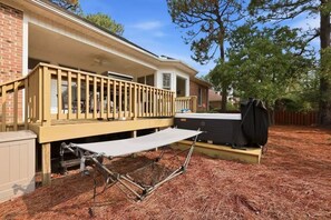 Una casa con porche cubierto, bañera de hidromasaje y terraza de madera.