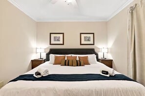 A neatly made bed with a dark headboard, two bedside lamps, and a framed picture on the wall. - Luxury Golf•Stay Simulator•Hot Tub•PGA Golden Tee (Pinehurst)