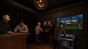 Zona de bar amb billar, televisió que mostra un partit de golf i un penjall.