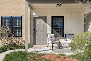 A residential entrance with a door marked '105', two chairs outside, and a brick wall with shutters. - Near Hospitals 2 bedroom 1 bath in Baton Rouge (Baton Rouge)