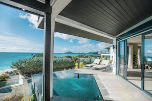 A modern outdoor pool area with clear blue water, lounge chairs, and a view of the ocean and distant mountains. - A Stay Worth Traveling For! Tropical Escape with Private Pool and Antigua Views! (Urlings)
