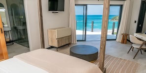 Habitació d'hotel amb llit, escriptori, cadira, televisió i vista a l'oceà.