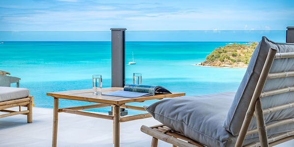 A beachside lounge with a table, chairs, and a view of the ocean. - Travel Better With a Stay Like This! 4BR Villa with Private Pool, Ocean Views! (Urlings)