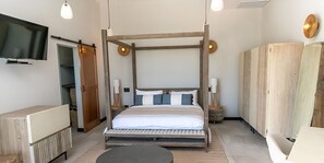 Un dormitori modern amb un llit amb cortines, taules de nit, televisió de pantalla plana i un armari.