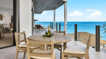 A wooden table with chairs on a balcony overlooking the sea.
