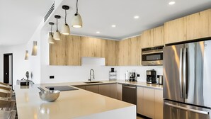 A modern kitchen with a large island, stainless steel appliances, and wooden cabinetry. - Ocean 20: Luxury 3-Bedroom Oceanfront Suite with Pool & Guest Cottage, Antigua (Urlings)