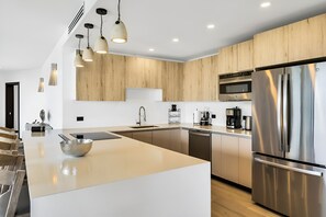 Una cocina moderna con una isla grande, electrodomésticos de acero inoxidable y armarios de madera.