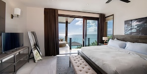 Habitació d'hotel moderna amb un llit gran, televisió de pantalla plana i un balcó amb vista a l'oceà.