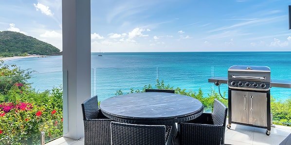 A balcony with a round table and chairs, a grill, and a view of the ocean. - Book Before It’s Gone! 2BR Villa with Panoramic Caribbean Views and Private Pool (Urlings)