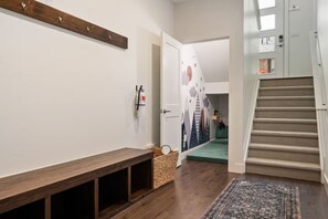 En hall med en träbänk, en brandsläckare, en flätad korg och en mönstrad matta.
