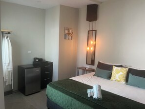 Ein Hotelzimmer mit einem Bett, einem Schminktisch, einem Spiegel und einer Wandleuchte.