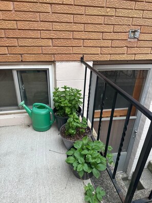 Ein Balkon mit Backsteinmauer, einem Fenster und einem Metallgeländer.