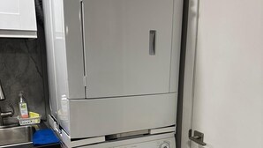 A compact laundry room with a stacked washer and dryer, a sink, and a blue towel. - Tamunas Studio ,ideally for mid and long stay (Hamilton)
