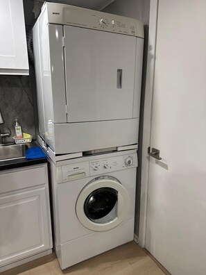 Ein kompakter Waschraum mit gestapelten Waschmaschine und Trockner, einem Waschbecken und einem blauen Handtuch.