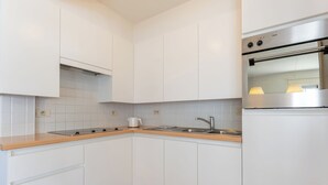 Una cocina moderna con armarios blancos, horno de acero inoxidable y encimera de madera.